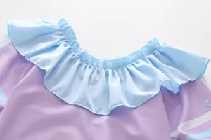 Détail d'un maillot de bain enfant lilas avec col à volants bleu clair et motif à bulles