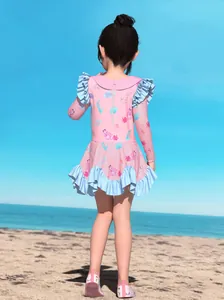 Outdoor back view of girls pink long sleeve swimsuit with ruffles and mermaid patterns