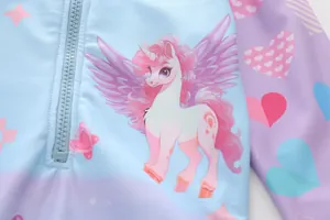 Detail of girls long sleeve swimsuit featuring a pink unicorn print and blue zipper