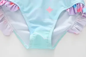 Detail of light blue girls' swimsuit featuring cloud patterns and rainbow ruffle edges