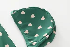 Detail of dark green swim cap with pink hearts and high-quality edge stitching detail
