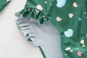Close-up of kids green one-piece swimsuit with colorful hearts and ruffle details
