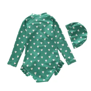 Detail of girls long sleeve swimsuit with heart print and matching floral swim cap