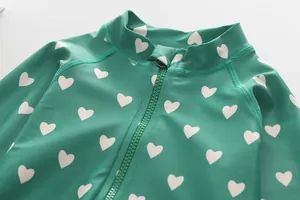 Detail of child swimsuit with green heart print, stand collar and protective zipper