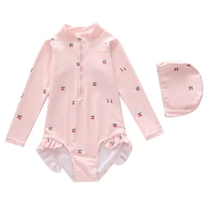 Detail of pink long sleeve girls swimsuit with cherry print and ruffled leg openings