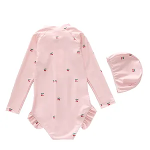 Detail of pink girls' long-sleeve swimsuit with cherry print and ruffled hem accents