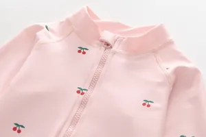 Close-up of kids' long sleeve swimsuit with pink cherry prints and smooth zipper detail