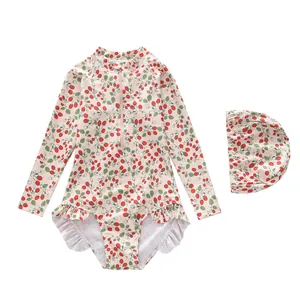 Detail of girls long sleeve swimsuit with strawberry print and matching swim cap