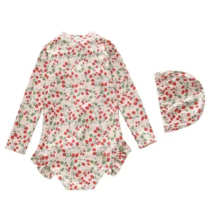 Detail of girls long sleeve strawberry print swimsuit with ruffled trim and matching swim cap