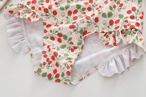 Detail of ruffled edges and vibrant strawberry floral print on long sleeve swimwear