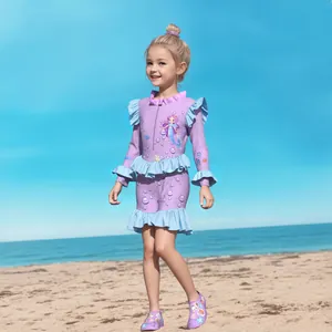 Detail of girls long sleeve swimsuit with ruffles, mermaid print and matching beach shoes