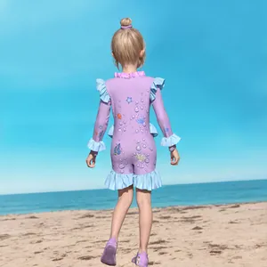 Detail of girls long sleeve swimsuit with ruffles and ocean cartoon print on beach