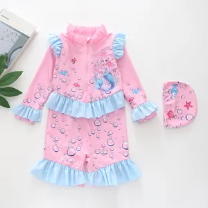 Detailed flat lay of pink long-sleeve kids swimsuit with mermaid prints and matching swim cap