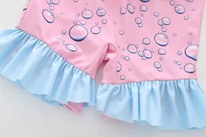Detail of pink girls' swimwear with blue ruffle trim and colorful polka dot pattern