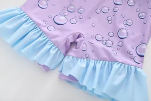 Detail of purple children's swimsuit featuring blue bubble print and ruffled leg hemline