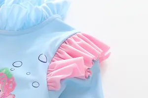 Detail of girls' light blue swimsuit with pink ruffled sleeves and cartoon mermaid print