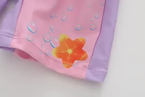 Détail du maillot de bain enfant rose et violet avec motifs d'étoiles de mer et coutures