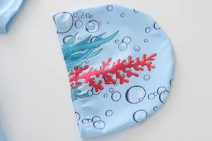 Gros plan du bonnet de bain enfant bleu clair avec motifs de coraux et algues