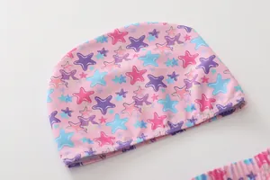 Detailed view of kids swimming cap with colorful star print and elastic pink fabric