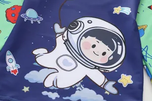 Detail of boys' swimwear showing cartoon astronaut and rocket prints on navy fabric