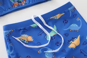 Dettaglio del costume da bagno blu da bambino con stampe di dinosauri e coulisse bianca