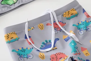 Dettaglio dei pantaloncini da nuoto bimbo con coulisse bianca e stampe dinosauri