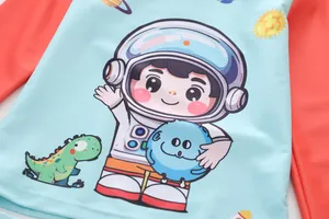 Detail of kids long sleeve swim top with astronaut and dinosaur print on blue fabric