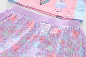 Close-up of girls mermaid swimsuit featuring pink ruffle top and mesh starfish bottoms