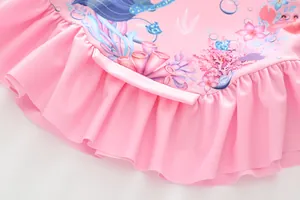 Détail d'un maillot de bain rose pour fille avec ourlet volanté et motifs d'océan