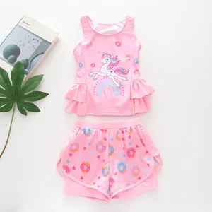 Flat lay of girls unicorn pink ruffles swimsuit with donut pattern shorts and green leaf decor
