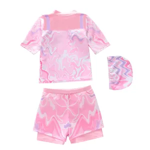 Three-piece girls swimsuit detail featuring ruffled marble print top, shorts and matching hat