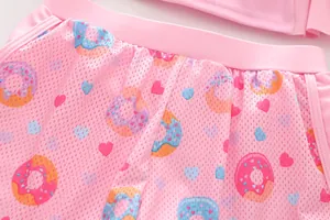 Detail of pink breathable mesh girls' swimwear bottom with colorful donut and heart patterns