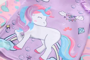 Detail of lavender long-sleeve kids swimsuit featuring a colorful unicorn and ruffles