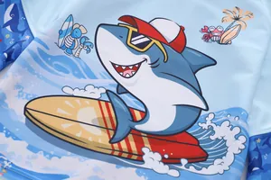 Detail of blue long-sleeve kids swimsuit featuring a surfing shark cartoon print