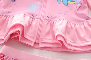 Detail of pink girls' long sleeve swimwear featuring a zipper and ruffled hem with ocean prints