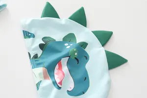 Detailansicht der hellblauen Kinderbadekappe mit süßem Dinosaurier-Muster und Flossen
