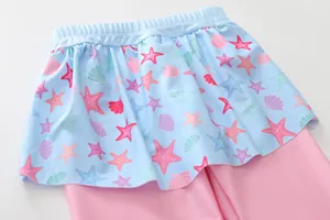Detail of girls two-piece swimsuit featuring sea shell prints and light blue ruffles
