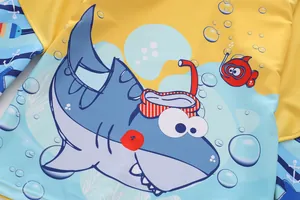 Close-up of kids wetsuit fabric featuring cartoon shark print and blue-yellow stitching