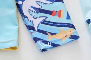 Detail of child swimsuit sleeve with blue stripes, shark print and yellow lining