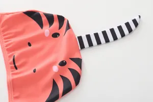 Detailansicht des orangefarbenen Stoffes mit Monstergesicht und gestreiftem 3D-Schwanz