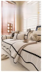 Detail of chenille sofa cover with ribbed texture and black wavy trim with pompoms