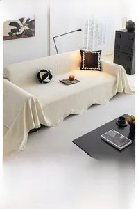 Gros plan détaillé du jeté de canapé en chenille crème avec texture jacquard et bords frangés