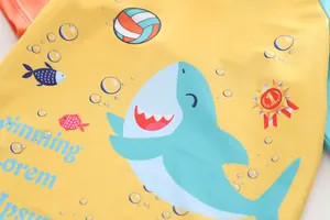 Dettaglio della stampa con squalo e pallavolo su costume giallo per bambini