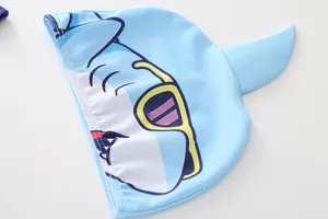 Detail der hellblauen Kinderbadekappe mit 3D Haifischflosse und Hai-Cartoon-Druck