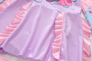 Vue détaillée d'un maillot de bain fille lilas avec volants roses et motifs marins