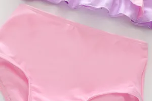 Détail du maillot de bain fille rose et violet avec volants et coutures précises