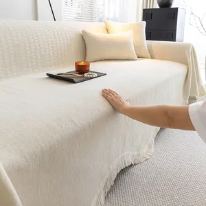 Housse de canapé en chenille beige avec texture géométrique en relief et finitions franges