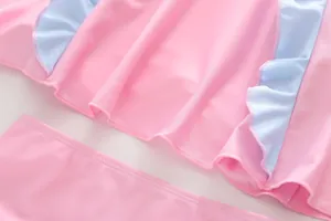 Détail de maillot de bain pour fille en tissu rose avec bords volantés bleu clair