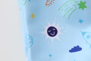 Close-up of children's swimwear fabric with light blue space and cartoon rocket pattern