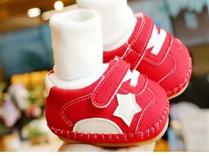 Detail of red baby walking shoes with white star patch and matching cotton socks